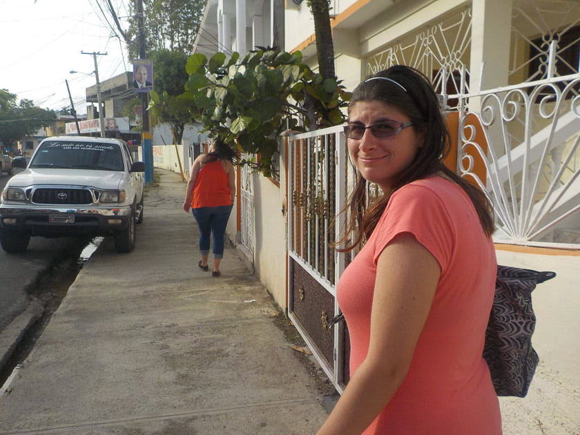 A woman smiling at the camera while walking down a street on vacation